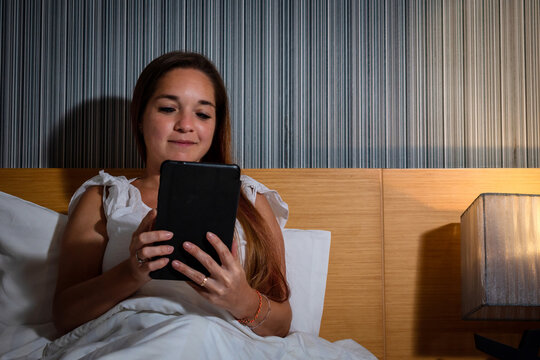 Mujer leyendo un libro digital en su cama, antes de dormir
