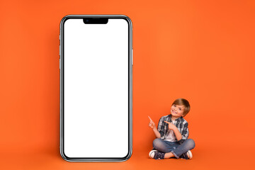 Full size photo of young boy indicate finger panel menu website recommend suggest isolated over orange color background