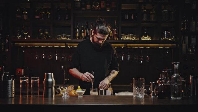 Professional bartender stirs cocktail in glass with spatula
