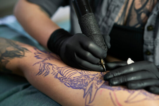 Close up of tattoo artist drawing on arm of client