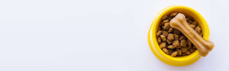 top view of yellow plastic bowl with pet food and dog treat isolated on white, banner.