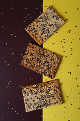Cereal bread with flax and sunflower seeds on brown and yellow background