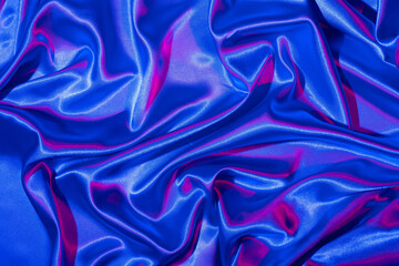 Textiles folds in neon blue-pink light. Trendy colors and shiny abstract background