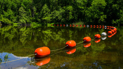 Orange buoys with reflection in river in springtime
