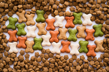 top view of bone shaped cookies and dry pet food as backdrop.