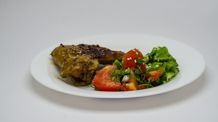 chicken wing, meat and vegetable salad on a white plate