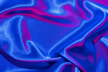 Textiles folds in neon blue-pink light. Trendy colors and shiny abstract background