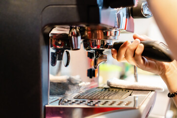 waitress fitting the filter holder in an industrial coffee machine