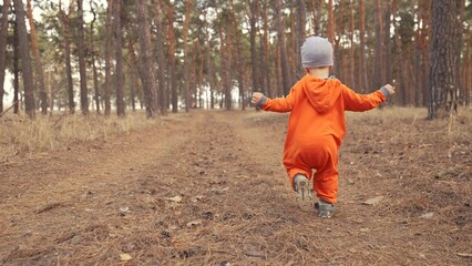 baby run. little boy in orange jumpsuit a walk through the forest park. kid dream happy family concept. baby run in fun the park. happy childhood carefree family walk child in the park