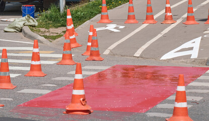 Red cones on pedestrian crossing. Road repairs, fences.