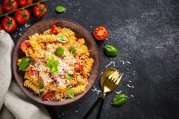 Italian pasta alla arrabiata with basil and parmesan on dark table. Top view image with space for design.