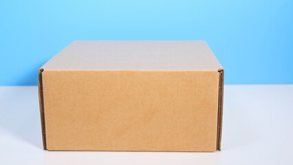 Brown cardboard box isolated on white table and blue background.