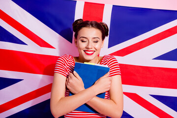 Portrait of cheerful cute girl closed eyes cuddle book isolated on great britain national flag