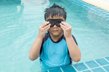 Close-up shot of a boy putting on swim goggles.