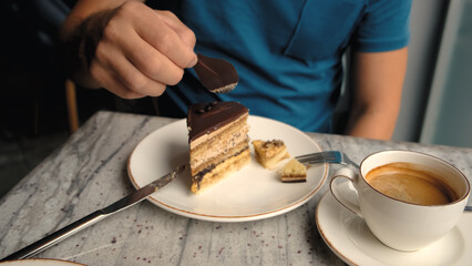 a man in a cafe eats chocolate decor from a cake