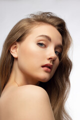 Fototapeta premium Glamour portrait of beautiful woman model with fresh daily makeup and romantic wavy hairstyle. Fashion shiny highlighter on skin, sexy gloss lips make-up and dark eyebrows