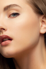 Close up beauty of a half face of a woman with wet radiant skin and big gray eyes. Fashionable...