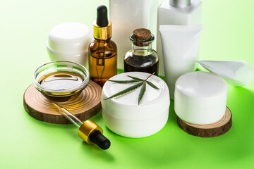 Cannabis cosmetic products at green background. Natural cosmetic concept. Cream, soap, serum, essential oil and others.