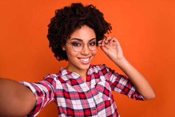Portrait of positive pretty person take selfie record video arm touch glasses isolated on orange color background