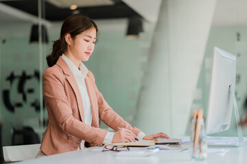 Attractive Asian businesswoman sitting on a computer in the office Prepare a report on the calculation of the amount in the documents of the Internal Revenue Service