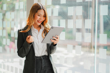 Pretty businesswoman holding a digital tablet while standing in the office with copy space 