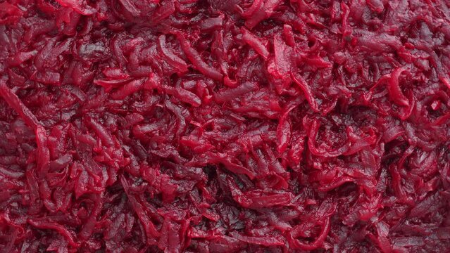 Background and texture of raw fresh juicy grated red beetroot vegetable, close up, top view, rotates