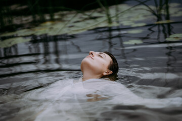 Beautiful young woman swimming in in the forest lake