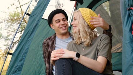 Romantic couple camping outdoors and sitting in a tent. Happy Man and woman on a romantic camping vacation.