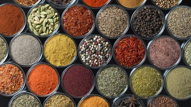 Assortment of aromatic spices, seeds and dry herbs for cooking food on background rotating in smal glass bowls rotating, close up, top view