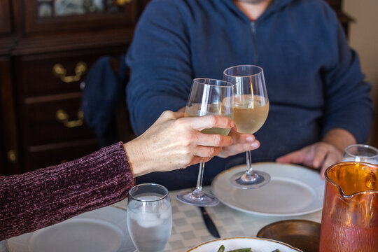 A Celebratory Toast Of White Wine At A Home Dinner By A Man And A Woman With A Set Table And Green Beans Nearby