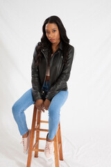 Pensive woman in a leather jacket sitting on a stool