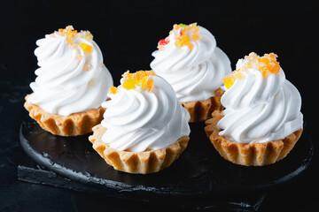 Mini cake basket with meringue cream on a black background