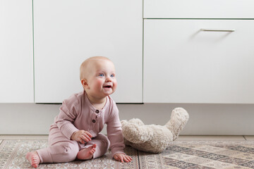 Cute cheerful baby sitting on the floor in kitchen