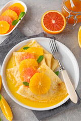 Naklejka na ściany i meble Delicious crepes suzette with orange syrup and slices fruits on a plate on a gray concrete background, top view