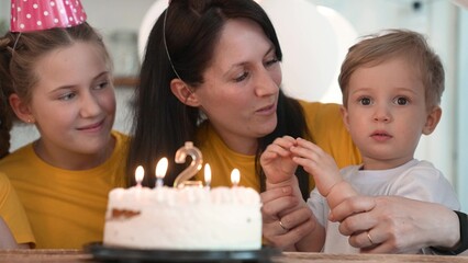 birthday. happy family on holiday party. parents and childs with baby getting ready to blow out birthday cake with candles. happy family fun at birthday. baby blows out the candles on the cake