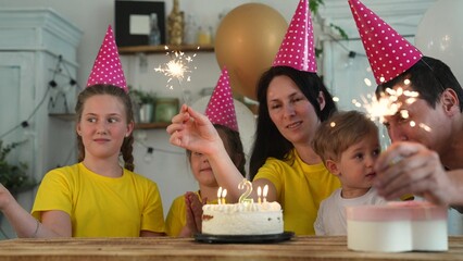 birthday. happy family on holiday party. parents and childs with baby getting ready to blow out fun birthday cake with candles. happy family at birthday. baby blows out the candles on cake