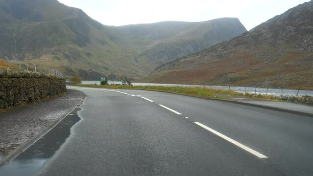Car windscreen view driving A5 Road on Llyn Ogwen lake side in autumn in North Wales, United Kingdom.