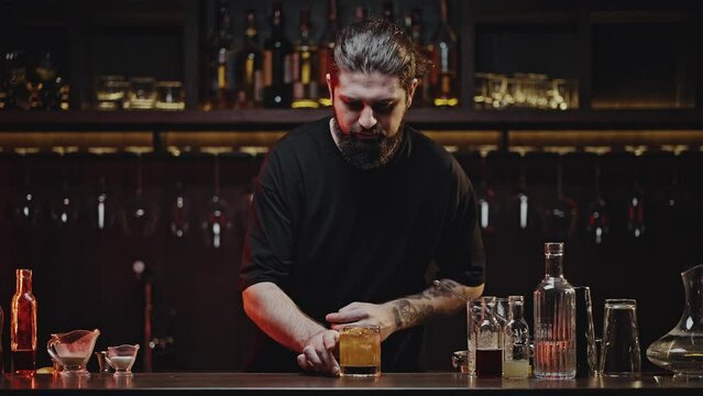Cool bartender decorates finished cold cocktail for client