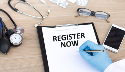 Register Now text on a piece of paper writes a doctor's hand on a table, a medical concept