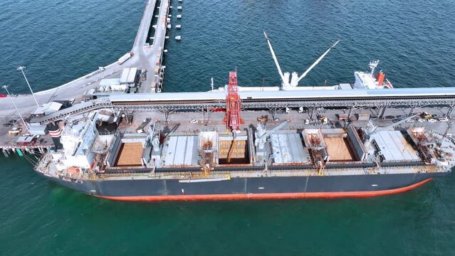Aerial top view of cargo container ship under the crane at the cargo international yard port under crane loading tank for export freight shipping by ship.