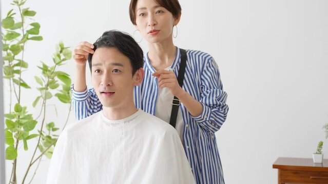 髪について相談する男性客と日本人美容師