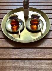 Turkish tea on a wooden background. Turkish tea in a traditional glass on a authentic metal tray. Morning breakfast drinking tea, Turkish culture.