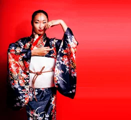 Foto op Plexiglas young pretty geisha on red background posing in kimono, oriental © iordani