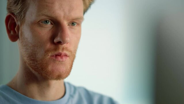 Serious guy looking monitor watching online blog on weekend evening closeup.