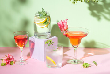 Colorful summer cocktails. Pop-art bar drinks set with  refreshing colorful summer detox drinks and flowers on pink and light green background 