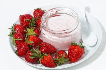 fruit yogurt in a glass jar and fresh strawberries, top view