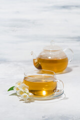 glass cup and teapot with jasmine green tea on a white background, vertical