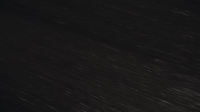 Fast movement ride along wet asphalt road with white dotted marking stripe lines on its surface, close-up down shot in the rainy autumn night.
