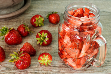 Cut strawberry fruits in a glass mug jar. Fresh berries fruit snack pieces.
