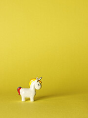 Unicorn little toy on yellow background with copy space. White unicorn with closed eyes. © Fotema